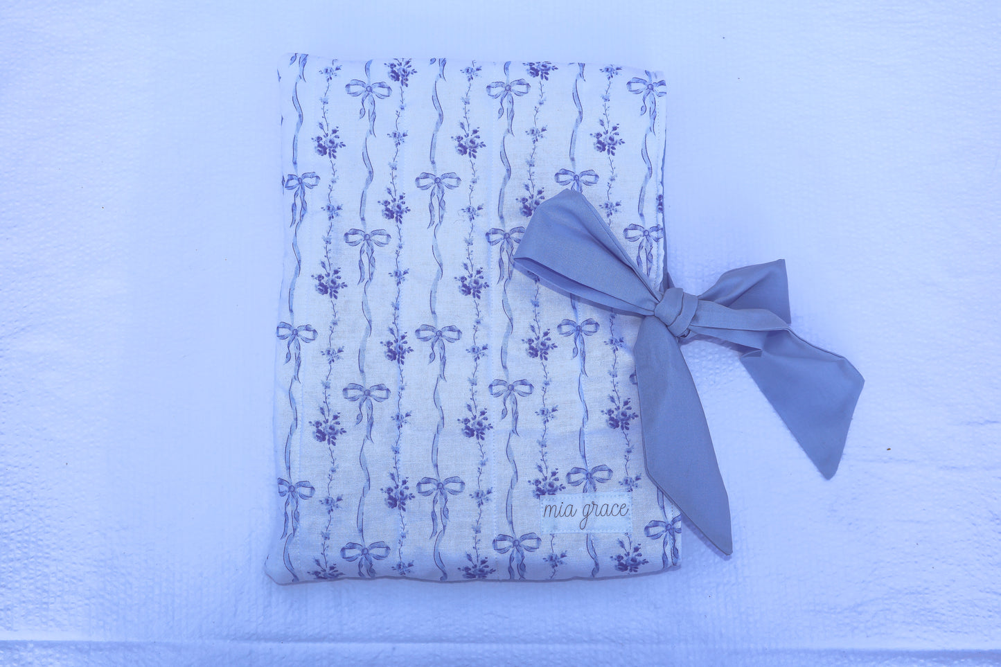 blue bow and floral fabric quilted bible or book sleeve with Mia grace brand label and a soft blue bow tied closure