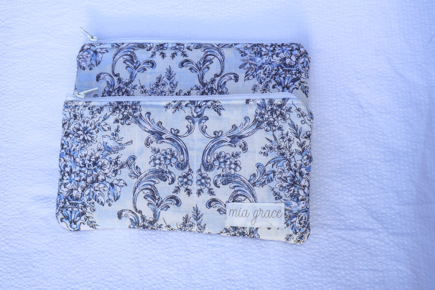 Blue floral patterned pouch with a zipper closure and a Mia grace brand label