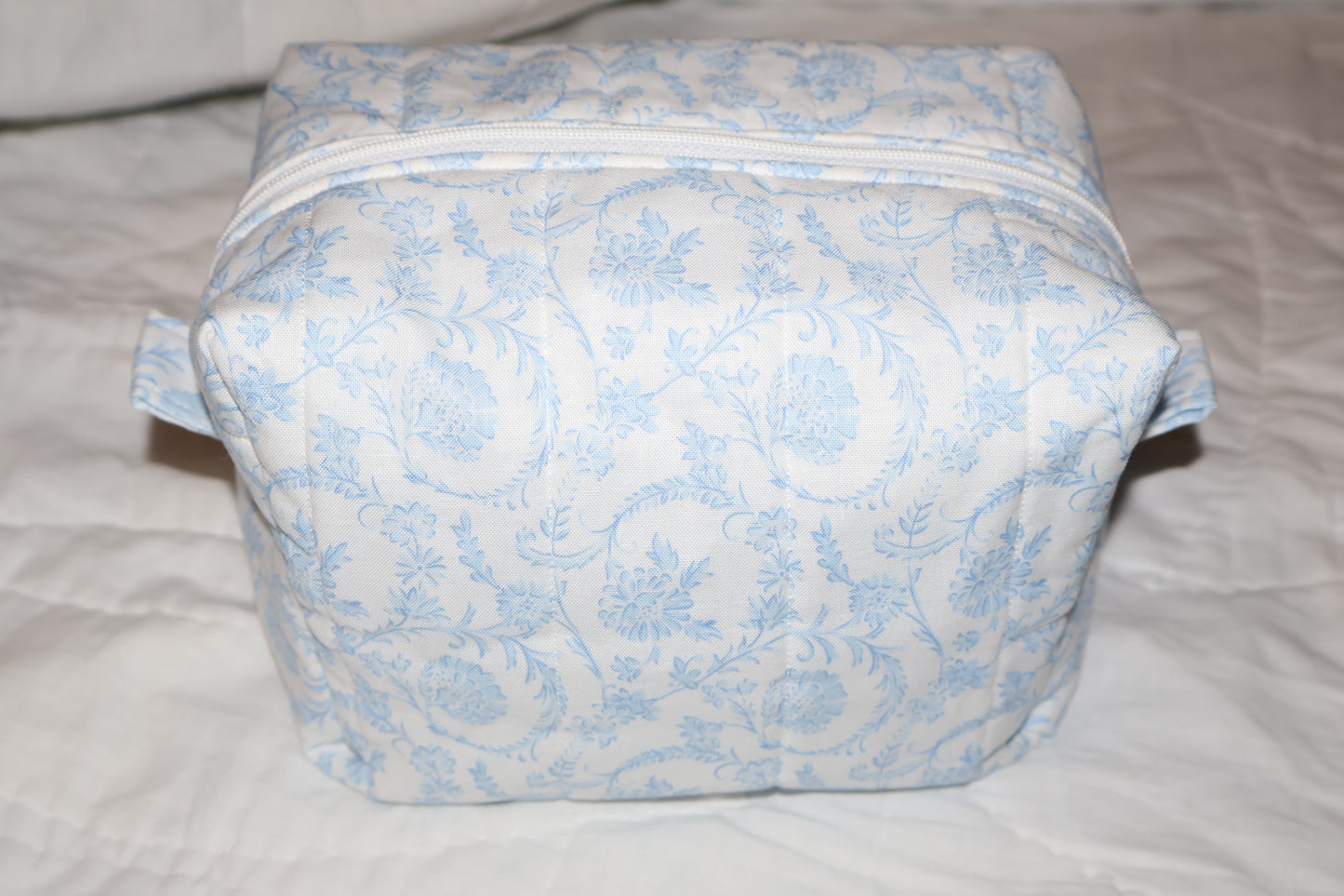 soft blue floral paisley quilted boxy pouch with a Mia Grace brand label and a white zipper and pull tabs.