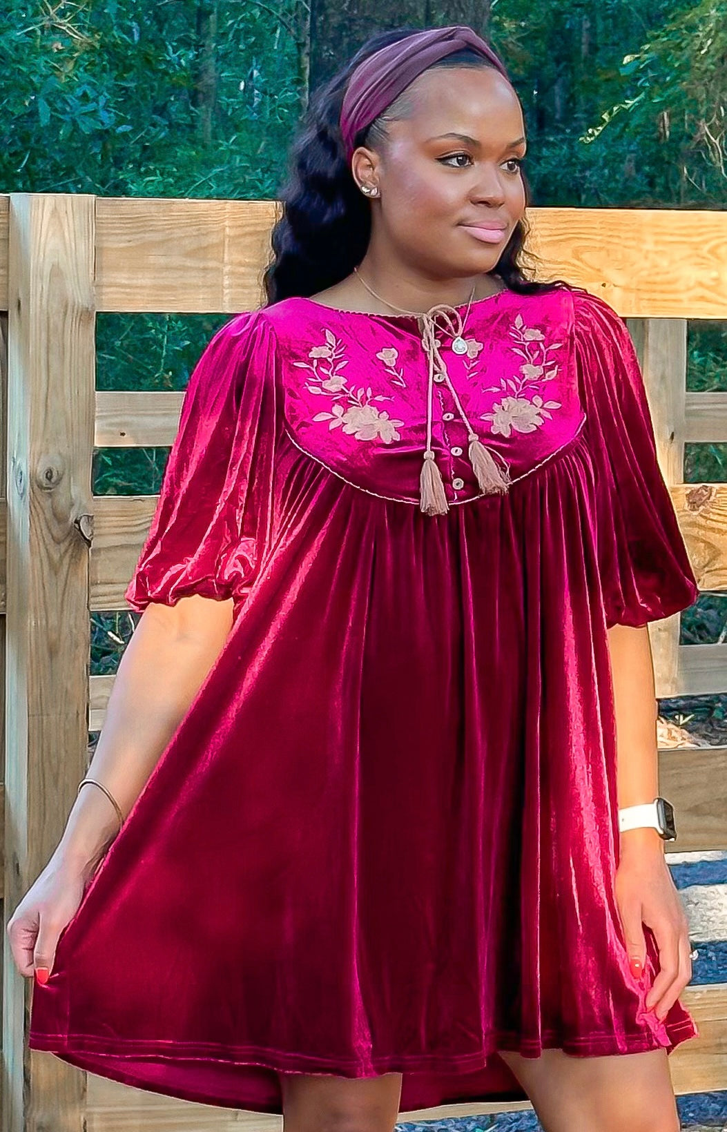 Maroon Dress with pleated detailing and scallop stitching details with floral embroidery on yoke and functional buttons with a tie tassel. Back paneling also has the floral embroidery detailing. The dress is short sleeve with flowy balloon sleeves.