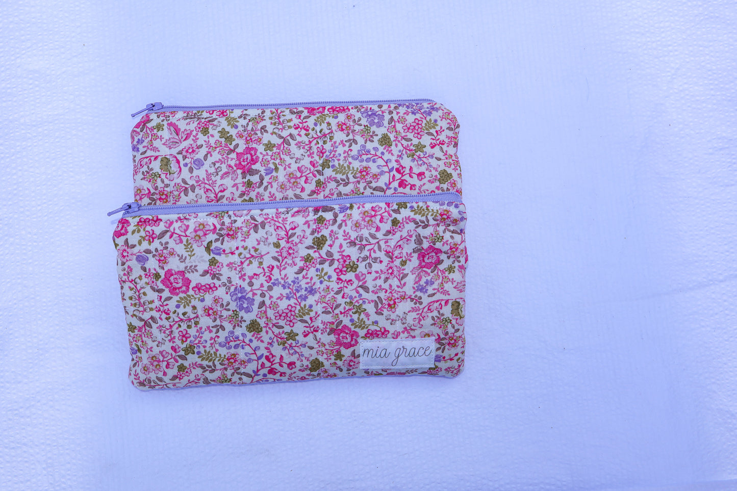 Fabric pouch with pink and purple floral pattern and 'mia grace' branding label 