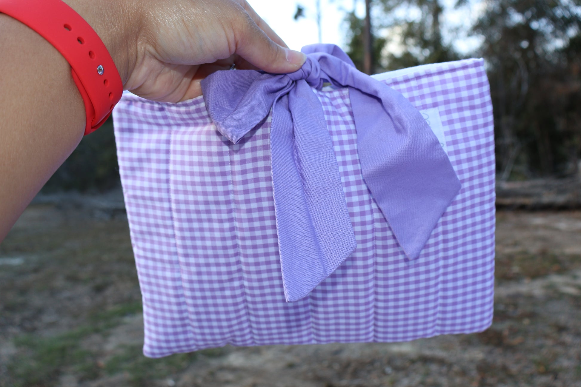 Purple gingham quilted bible or book sleeve with a purple fabric bow tied closure and a Mia grace brand label on the front bottom right. 