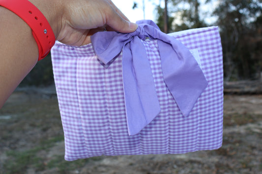 Purple gingham quilted bible or book sleeve with a purple fabric bow tied closure and a Mia grace brand label on the front bottom right. 