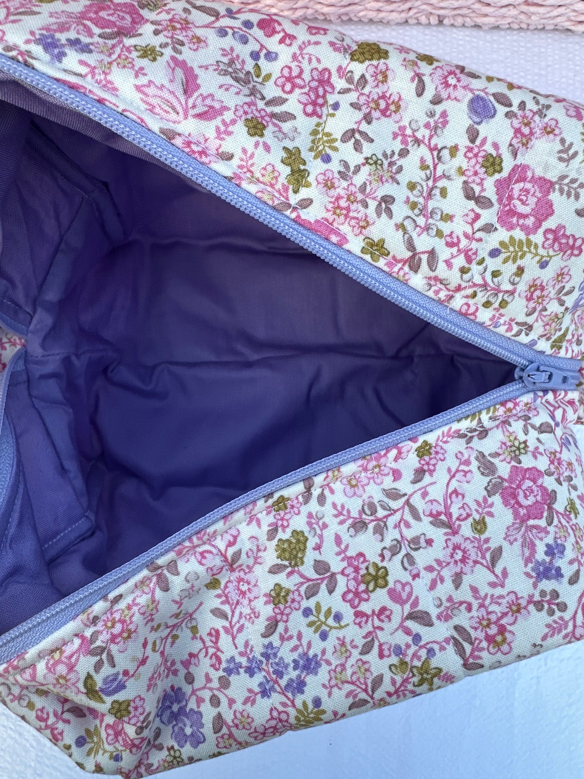 purple and pink floral-patterned quilted boxy pouch with a Mia Grace brand label and a purple zipper and pull tabs. Purple Inner Fabric