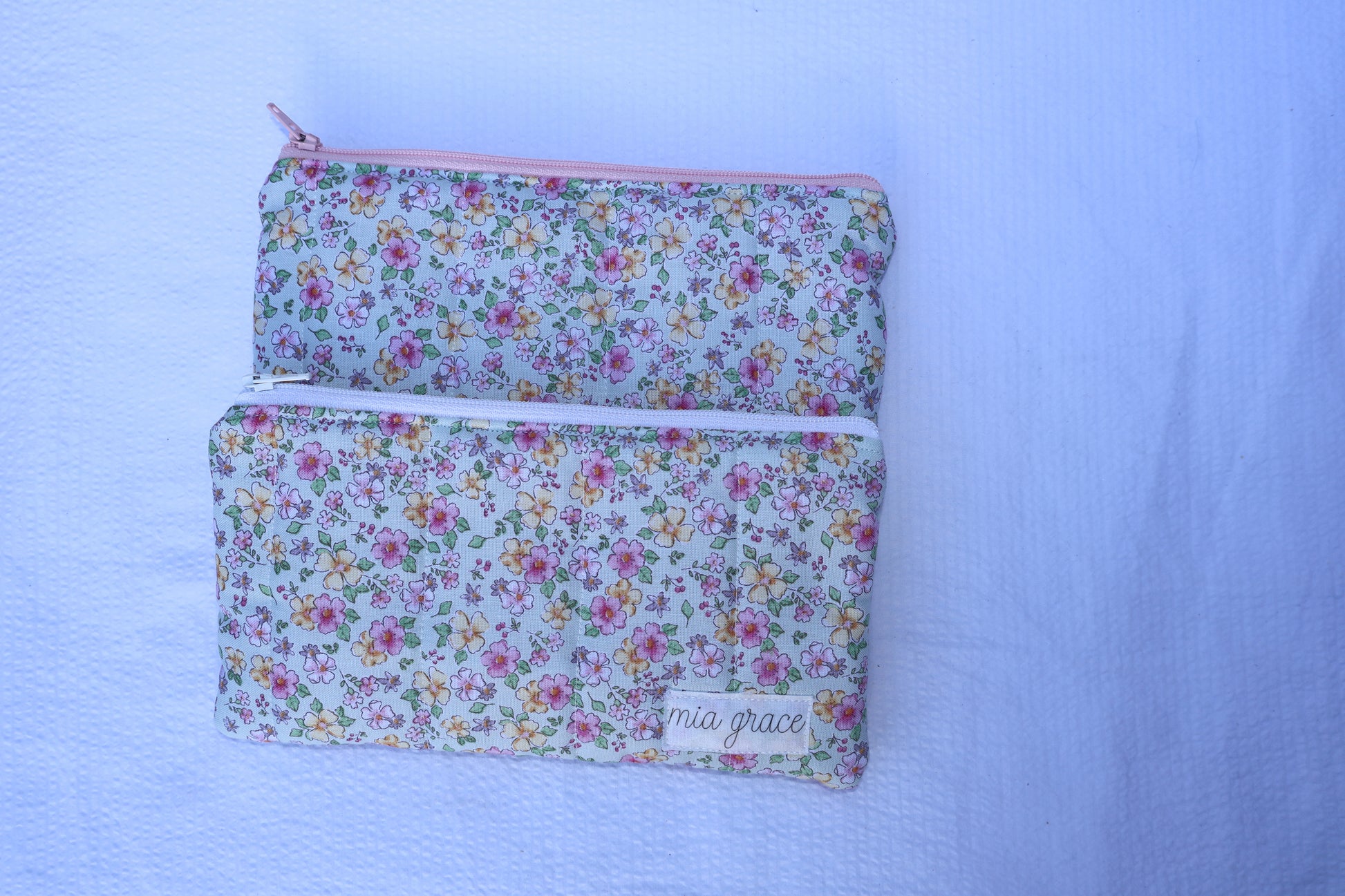 Blue floral patterned pouch with a zipper closure and a Mia grace brand label 