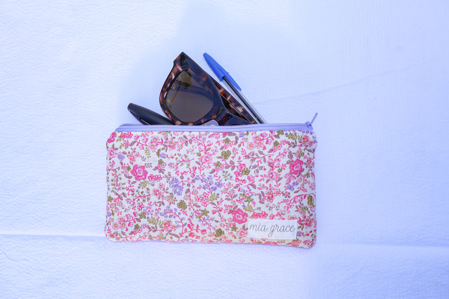 Fabric pouch with pink and purple floral pattern and 'mia grace' branding label 