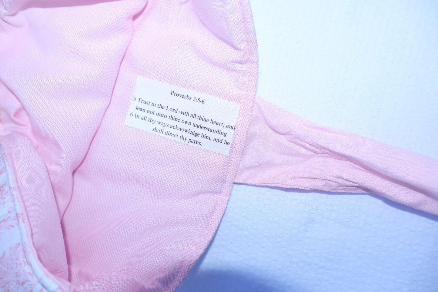 close up of proverbs chapter 5 verse 5 and 6 stitched on the inner fabric. soft pink inner fabric with a white label and black text.