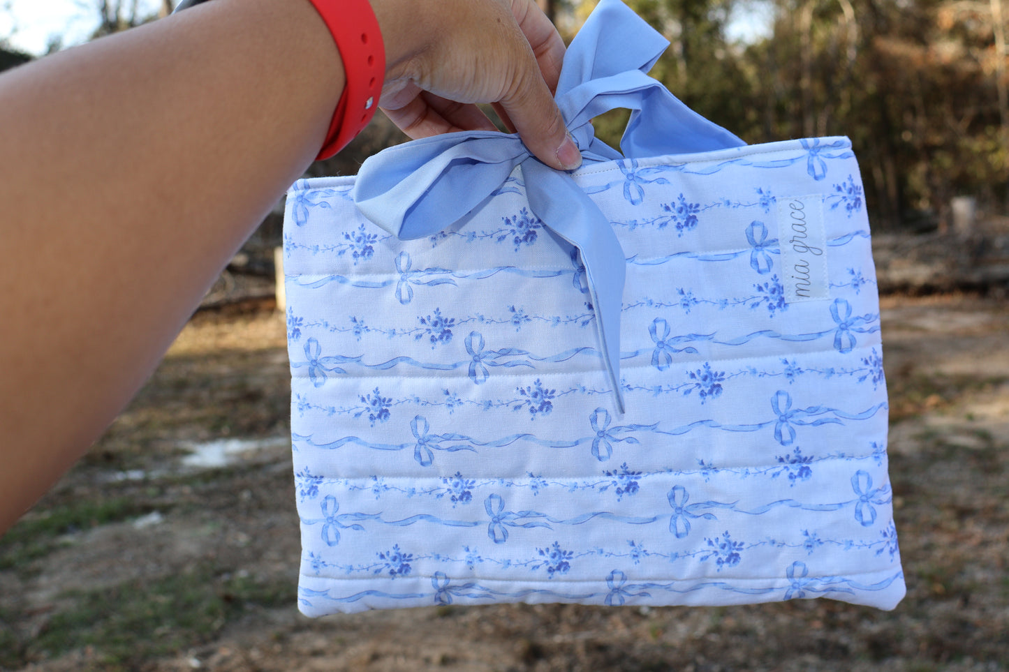 blue bow and floral fabric quilted bible or book sleeve with Mia grace brand label and a soft blue bow tied closure