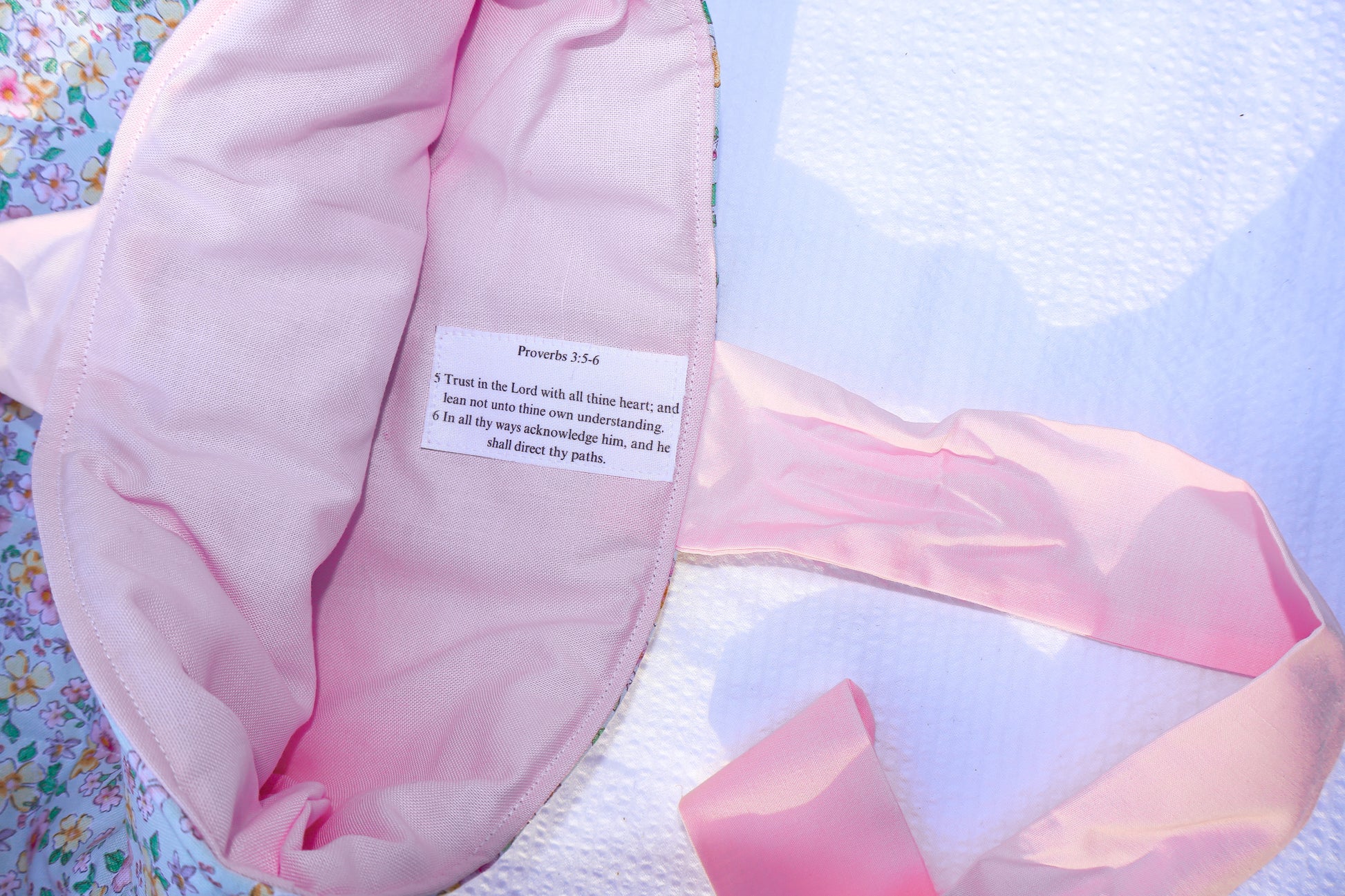 proverbs chapter 3 verse 5 and 6 on a label stitched into the inner  fabric of the bible sleeve. Inner fabric is soft pink and the scripture text is black on a white label.