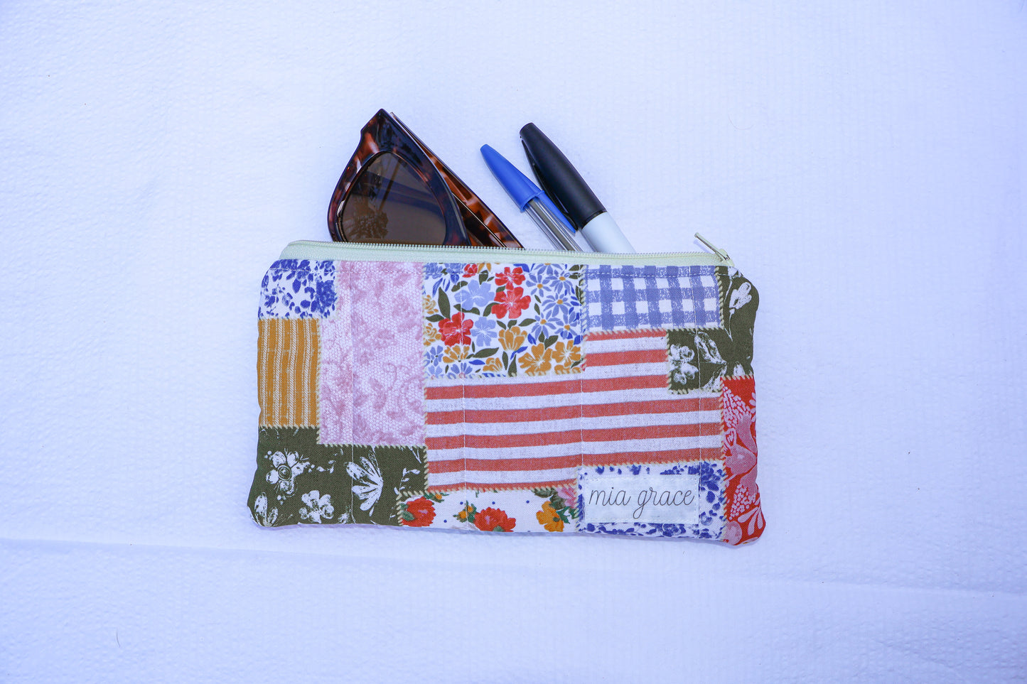 Patchwork fabric quilted pouch with a Mia grace branding label