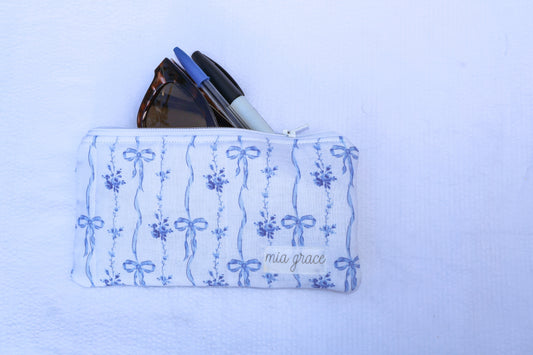 Fabric pouch with blue bow and floral patterns and 'mia grace' branding label 