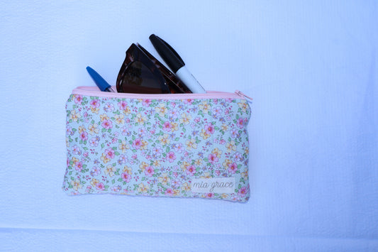 mint, pink, and yellow floral  patterned pouch with a zipper closure and a Mia grace brand label 