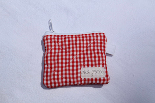 red and white gingham wallet sized pouch with a 'mia grace' brand label, zipper closure, and a hoop for a key ring to be attached. 