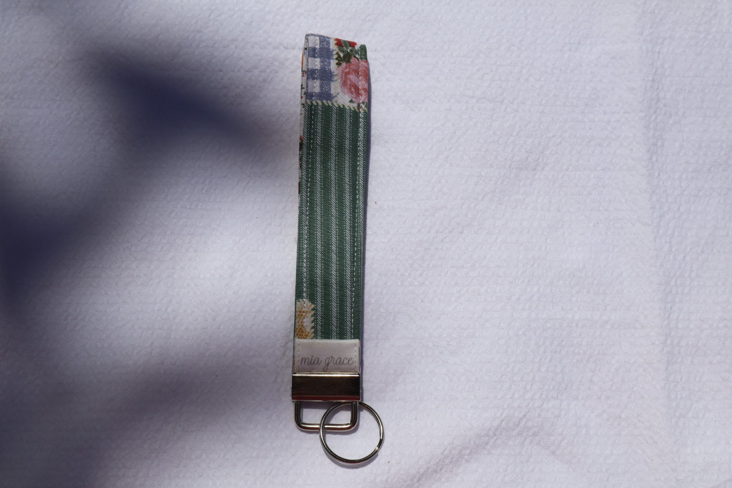 Fabric key fob with a patchwork pattern and a Mia grace brand label and a key ring