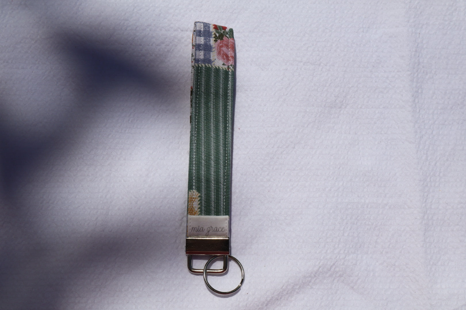Fabric key fob with a patchwork pattern and a Mia grace brand label and a key ring