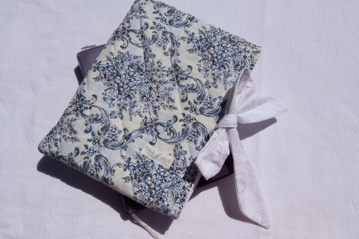 blue Floral-patterned fabric with a white bow tie closure and a Mia grace brand label