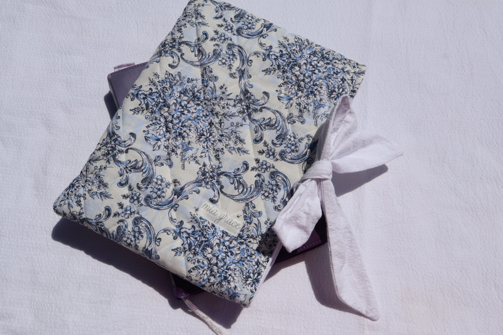 blue Floral-patterned fabric with a white bow tie closure and a Mia grace brand label