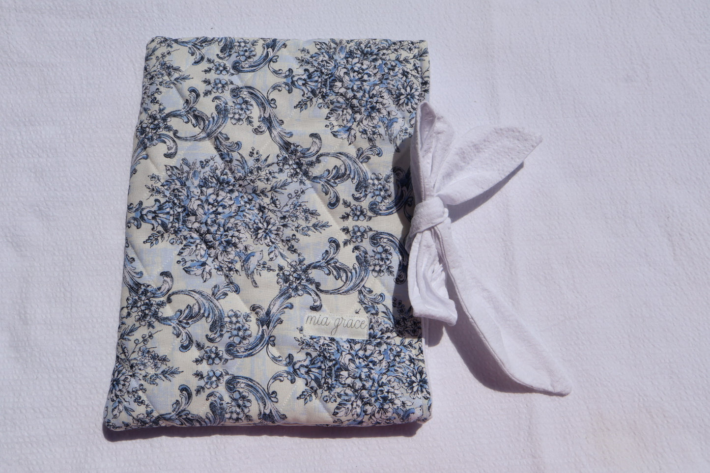 blue Floral-patterned fabric with a white bow tie closure and a Mia grace brand label