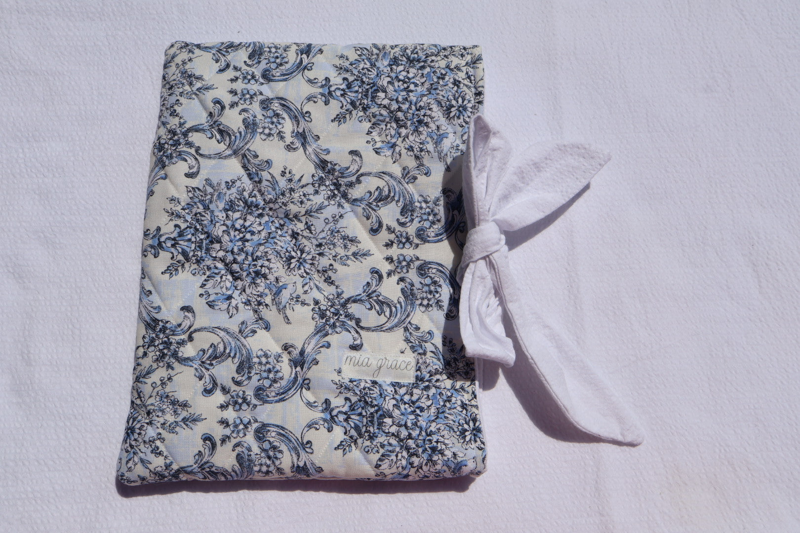 blue Floral-patterned fabric with a white bow tie closure and a Mia grace brand label