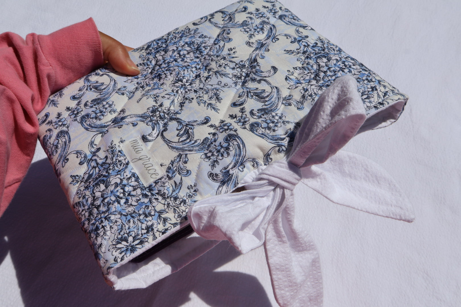blue Floral-patterned fabric with a white bow tie closure and a Mia grace brand label