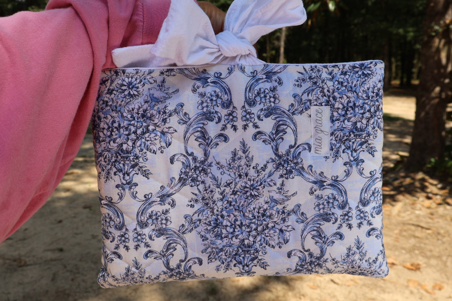 blue Floral-patterned fabric with a white bow tie closure and a Mia grace brand label
