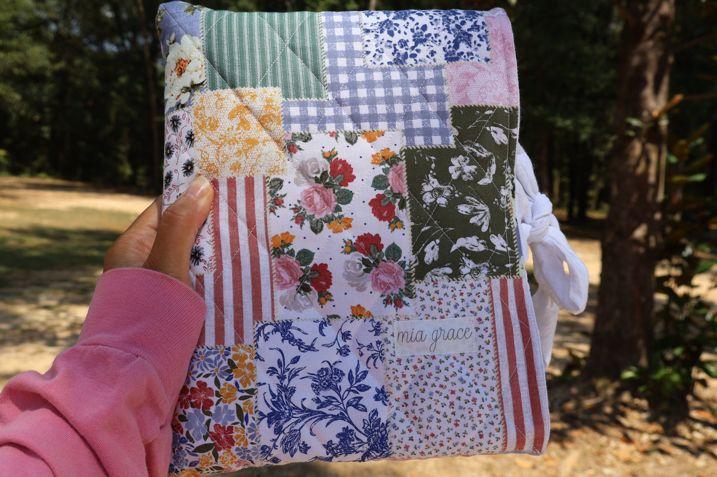 patchwork fabric quilted bible or book sleeve with Mia grace brand label and a white bow tied closure 