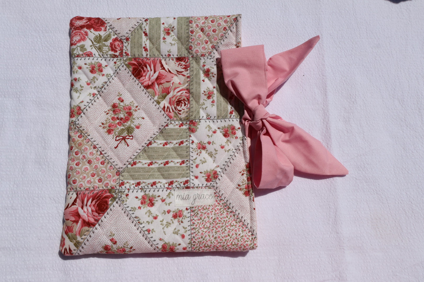Patchwork Floral pink and green fabric  and a pink ribbon  bow tie closure and a Mia grace branding label