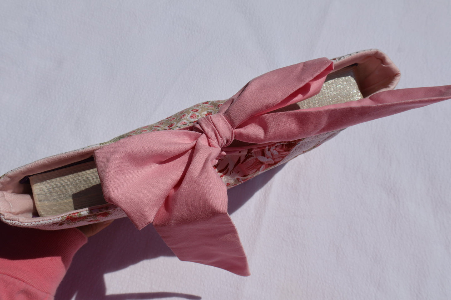 Patchwork Floral pink and green fabric  and a pink ribbon  bow tie closure and a Mia grace branding label with a bible displayed inside