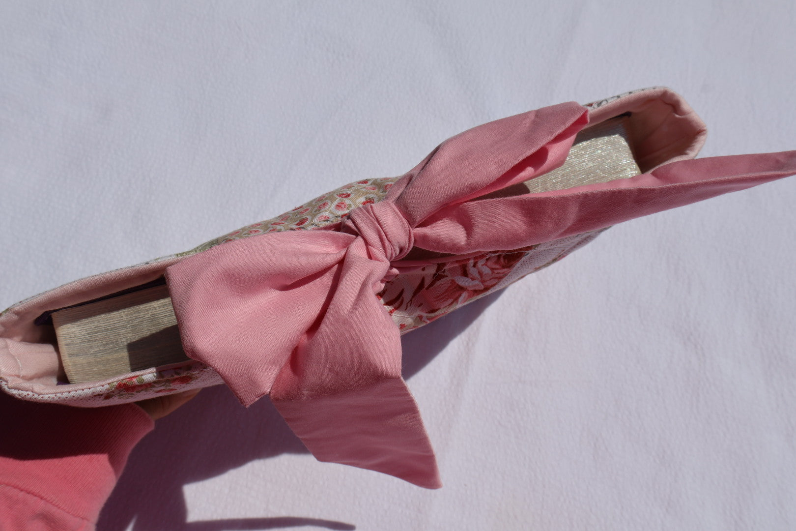 Patchwork Floral pink and green fabric  and a pink ribbon  bow tie closure and a Mia grace branding label with a bible displayed inside