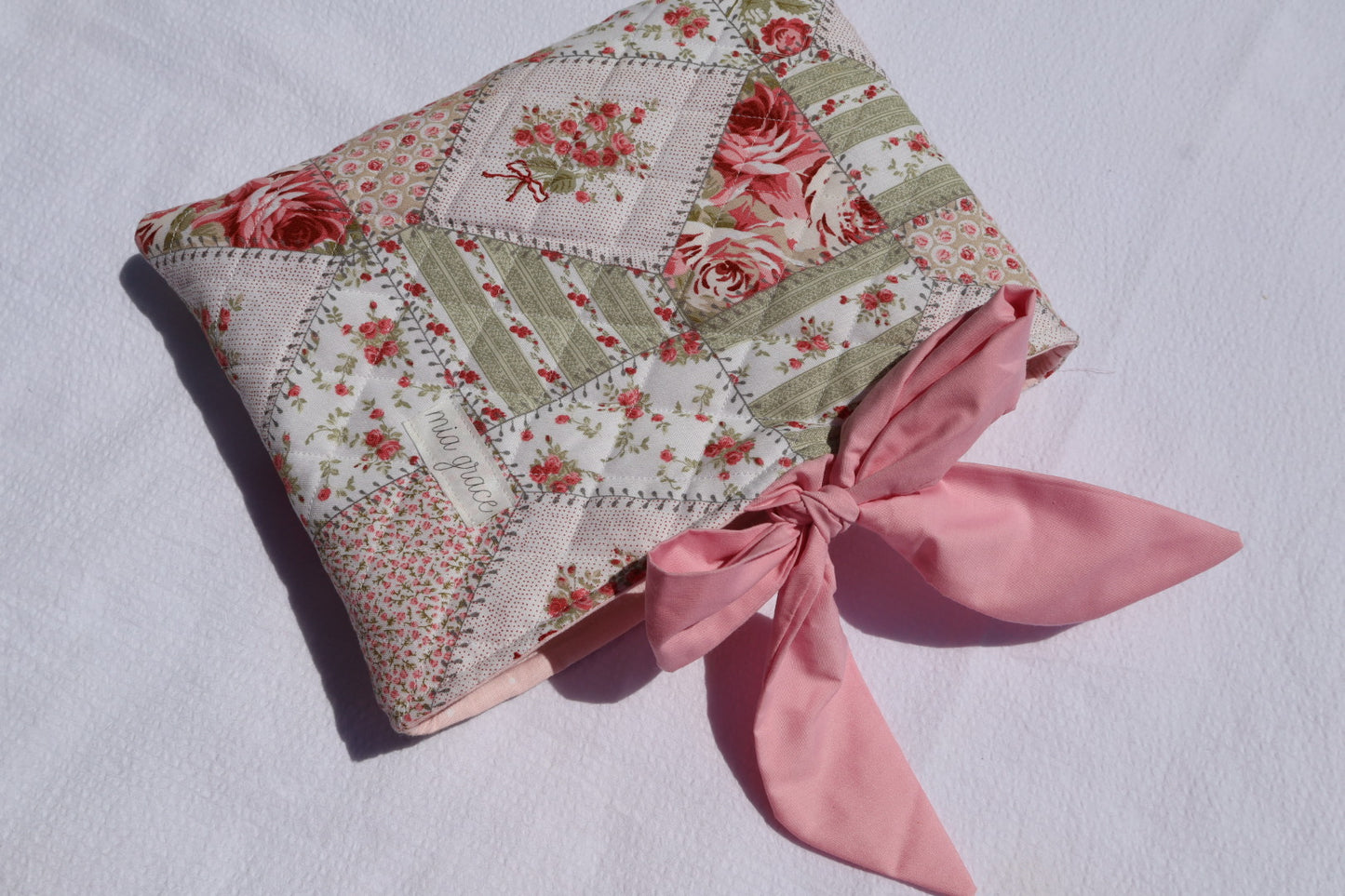 Patchwork Floral pink and green fabric  and a pink ribbon  bow tie closure and a Mia grace branding label