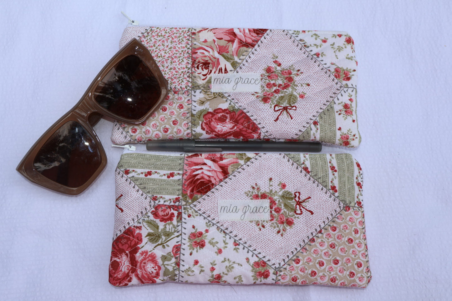 Floral patchwork patterned pouch with 'mia grace' branding label with a zipper closure