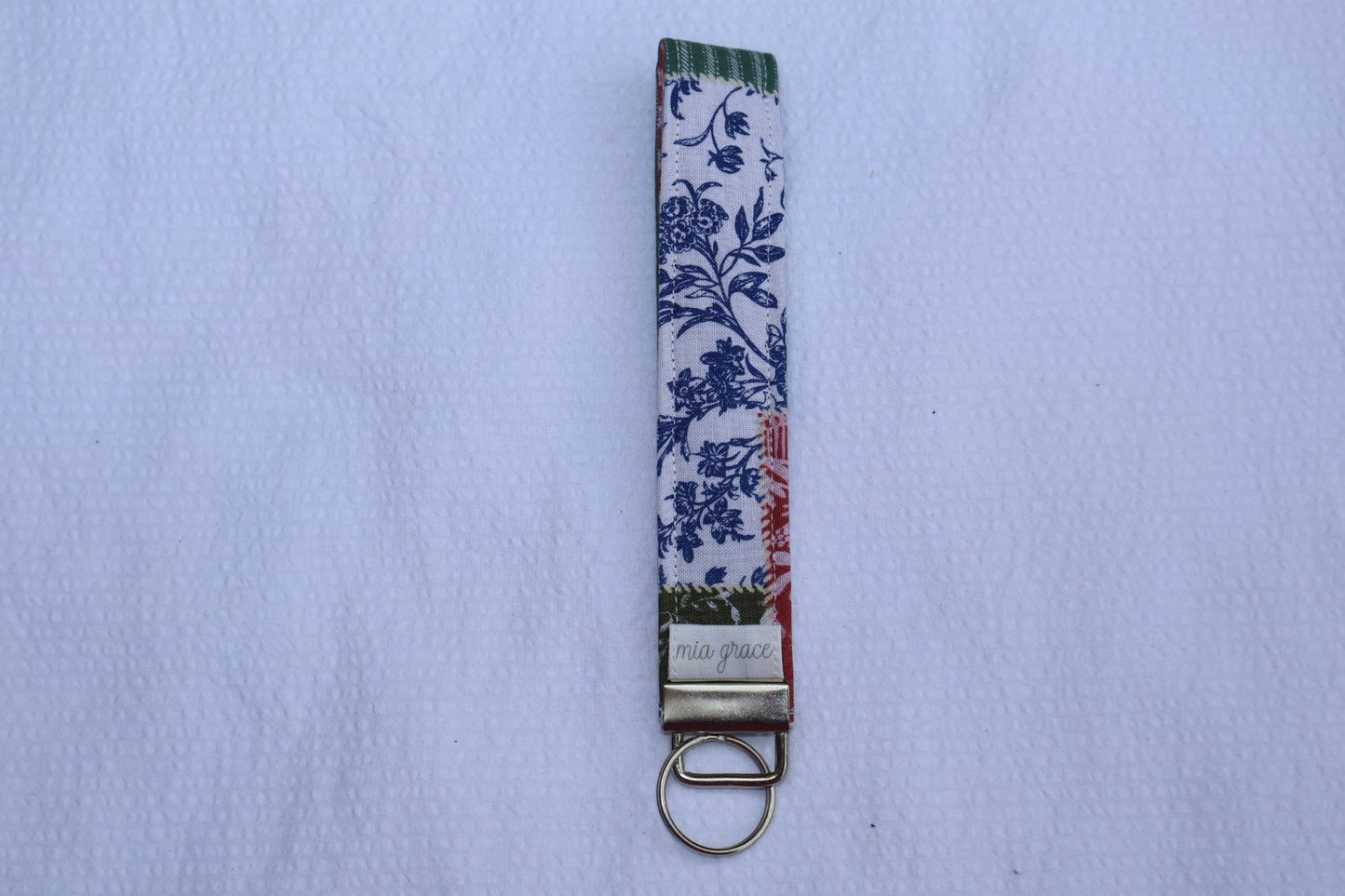Fabric key fob with a patchwork pattern and a Mia grace brand label and a key ring