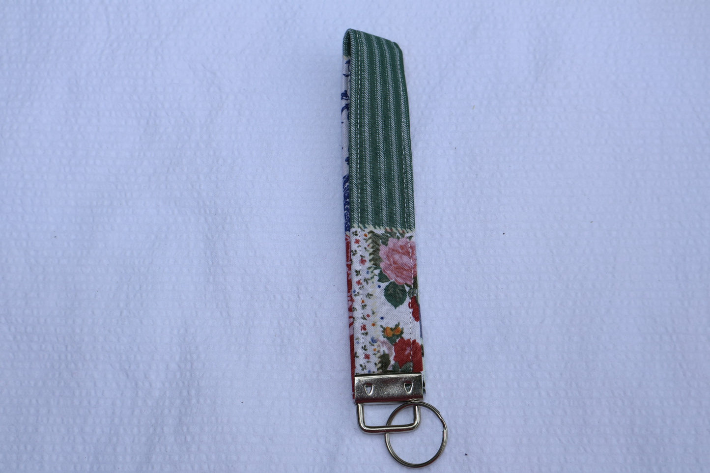 Fabric key fob with a patchwork pattern and a Mia grace brand label and a key ring