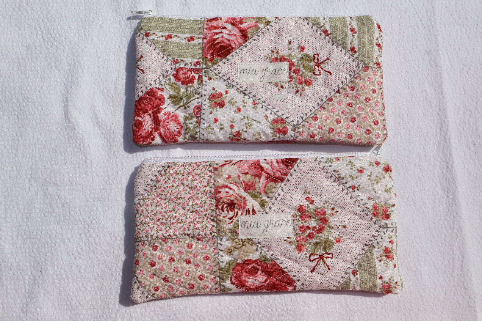 Floral patchwork patterned pouch with 'mia grace' branding label with a zipper closure