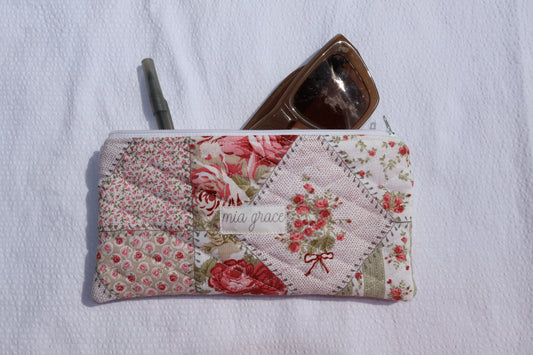 Floral patchwork patterned pouch with 'mia grace' branding label with a zipper closure
