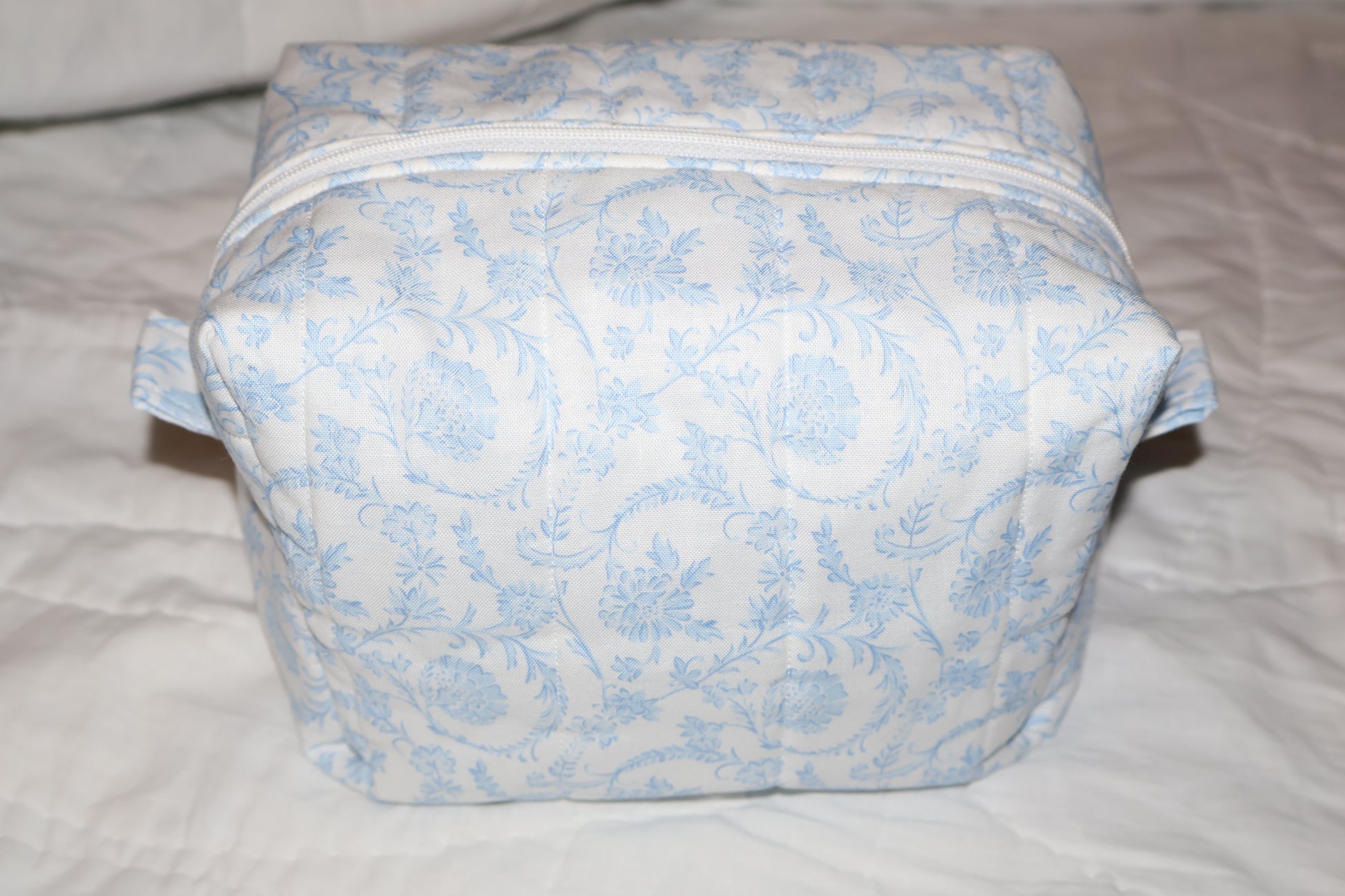 soft blue floral paisley quilted boxy pouch with a Mia Grace brand label and a white zipper and pull tabs.