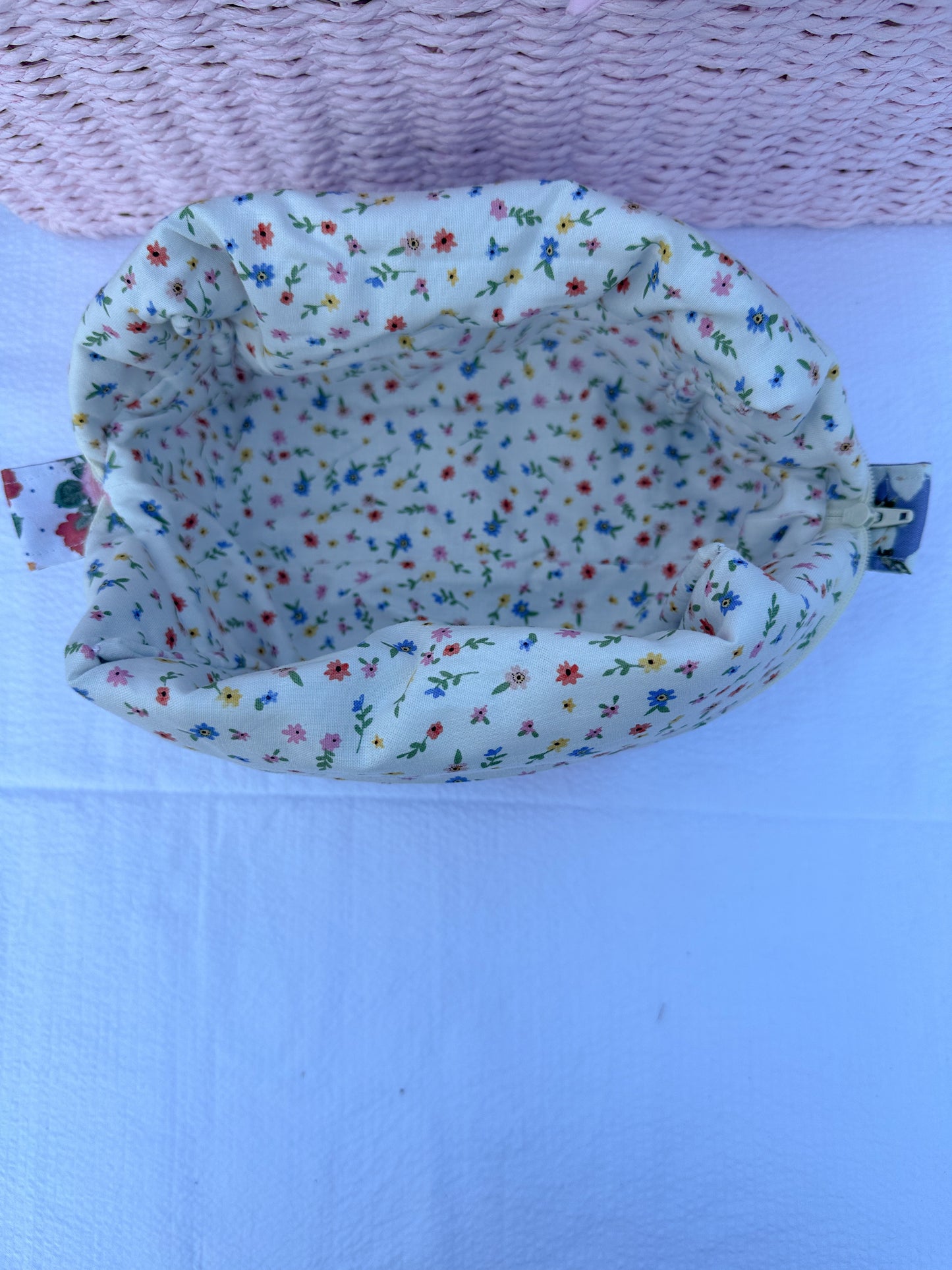 Patchwork-style fabric quilted boxy pouch with floral and gingham  patterns with a Mia grace brand label and cream zipper with cream  lace trim and pull tabs. Ditsy wildflowers floral inner fabric