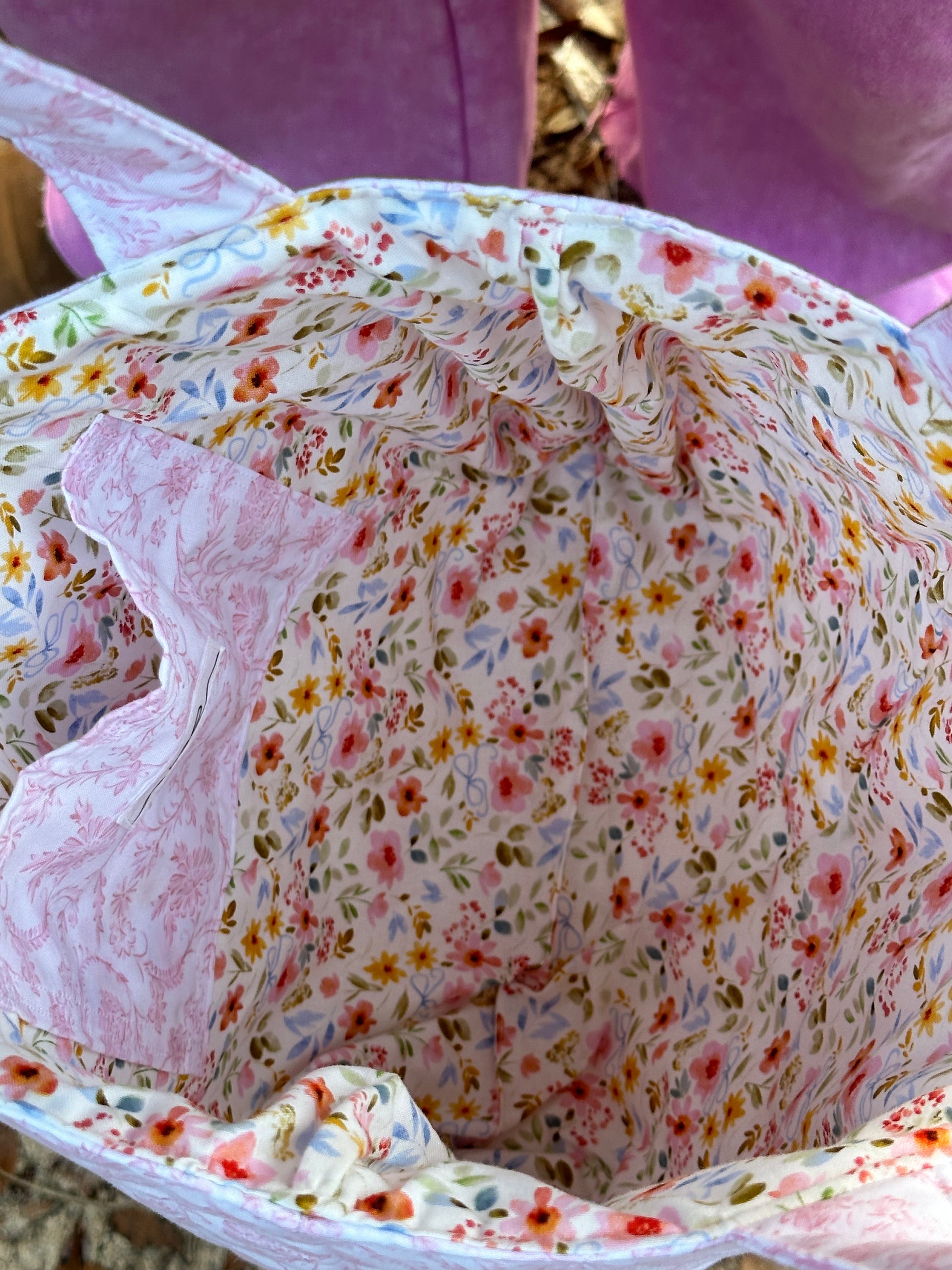 Tote bag has an inner pocket with a bow label that matches outer fabric. inner fabric is a floral print with blue bows. 