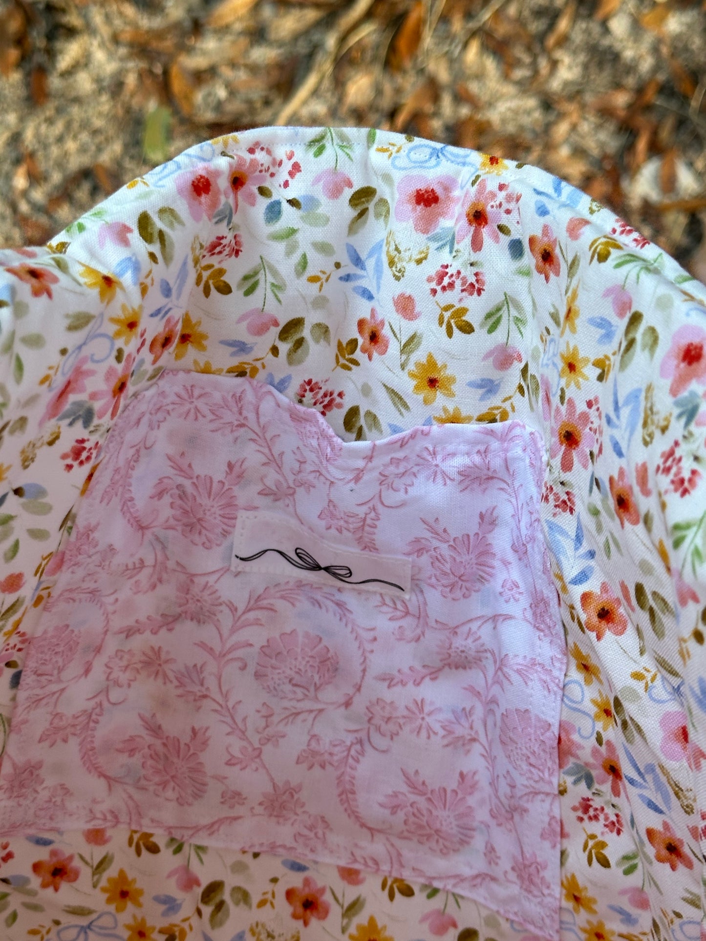 Tote bag has an inner pocket with a bow label that matches outer fabric. inner fabric is a floral print with blue bows. 