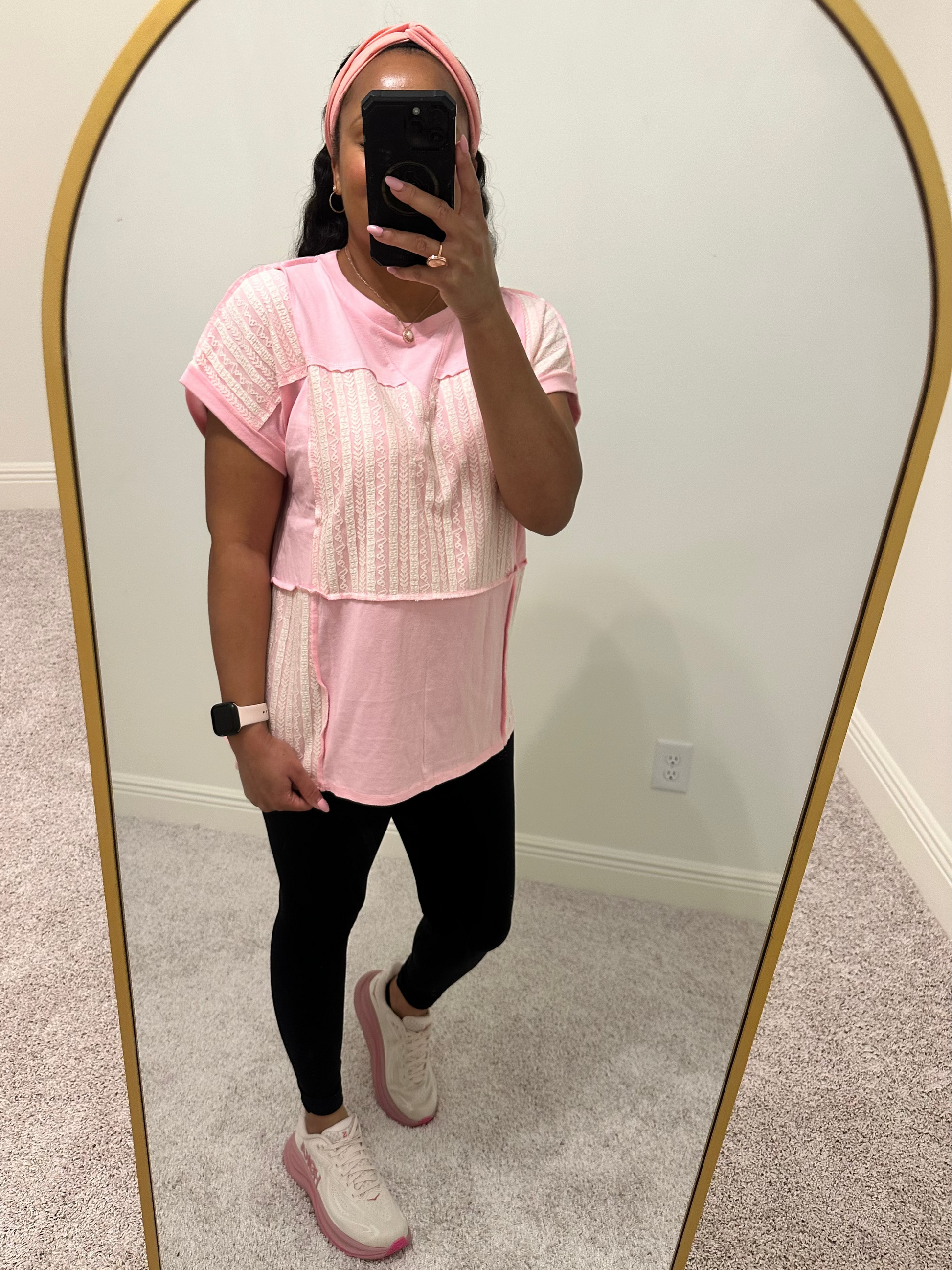 Person wearing a pink shirt with white lace patchwork detailing that is a relaxed fit. 