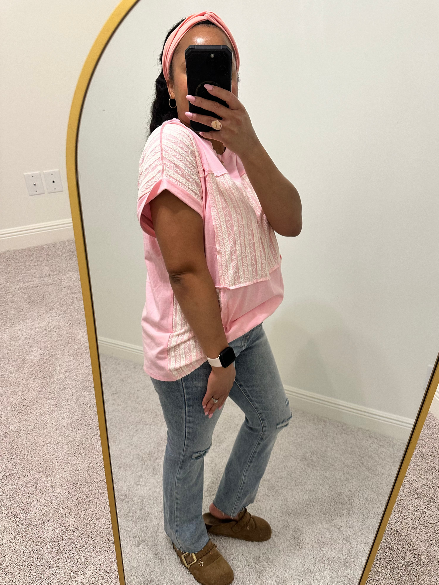 Person wearing a pink shirt with white lace patchwork detailing that is a relaxed fit. 