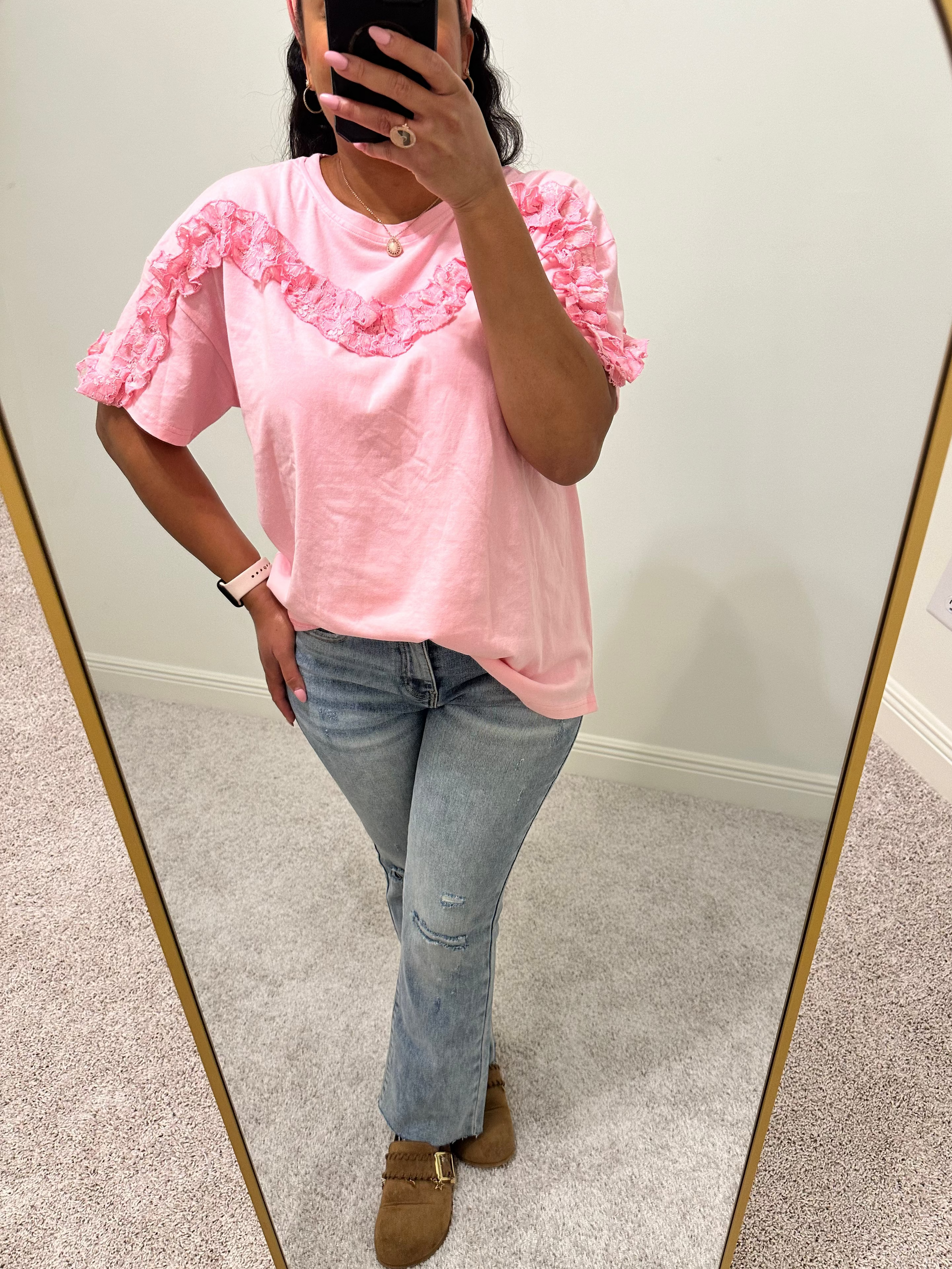 Person wearing a pink lace ruffled trim detailed short sleeve top.