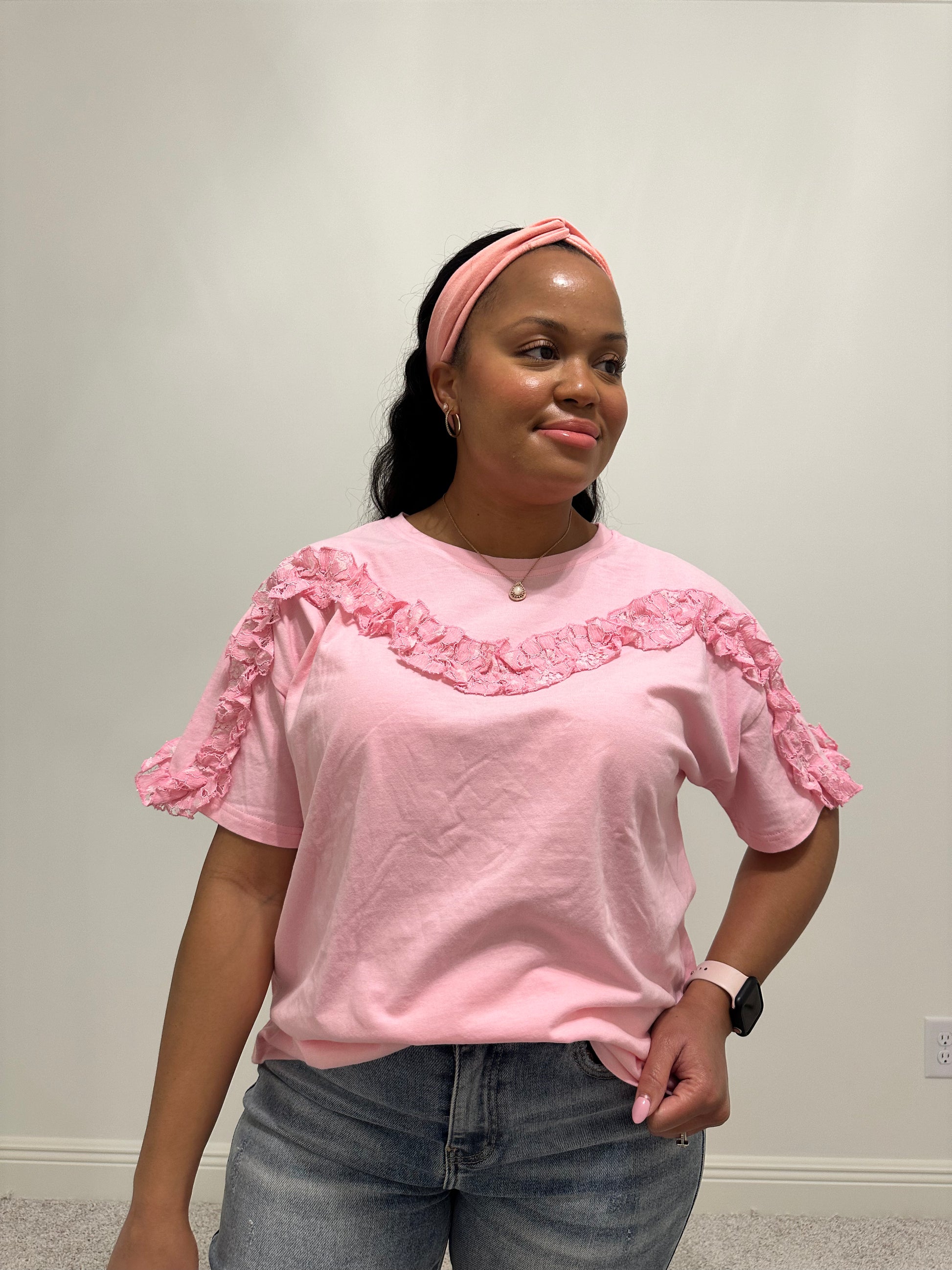 Person wearing a pink lace ruffled trim detailed short sleeve top.
