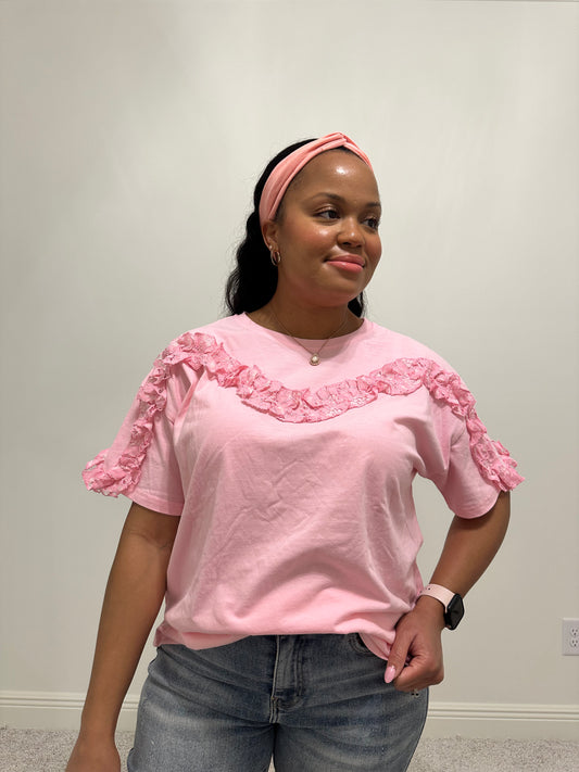 Person wearing a pink lace ruffled trim detailed short sleeve top.