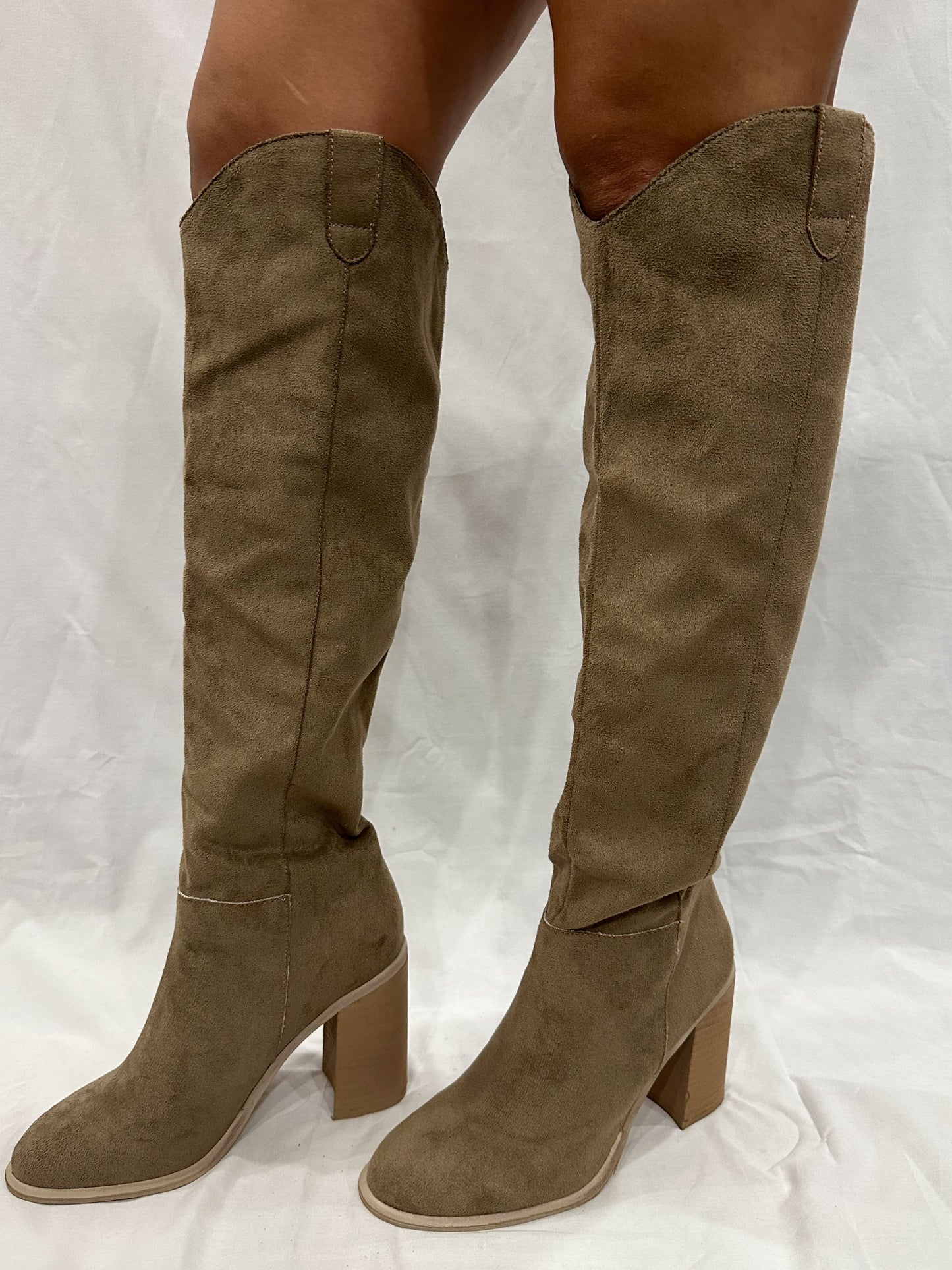 A pair of taupe grey knee-high boots with a cowgirl style, tall heel, and rounded toe.