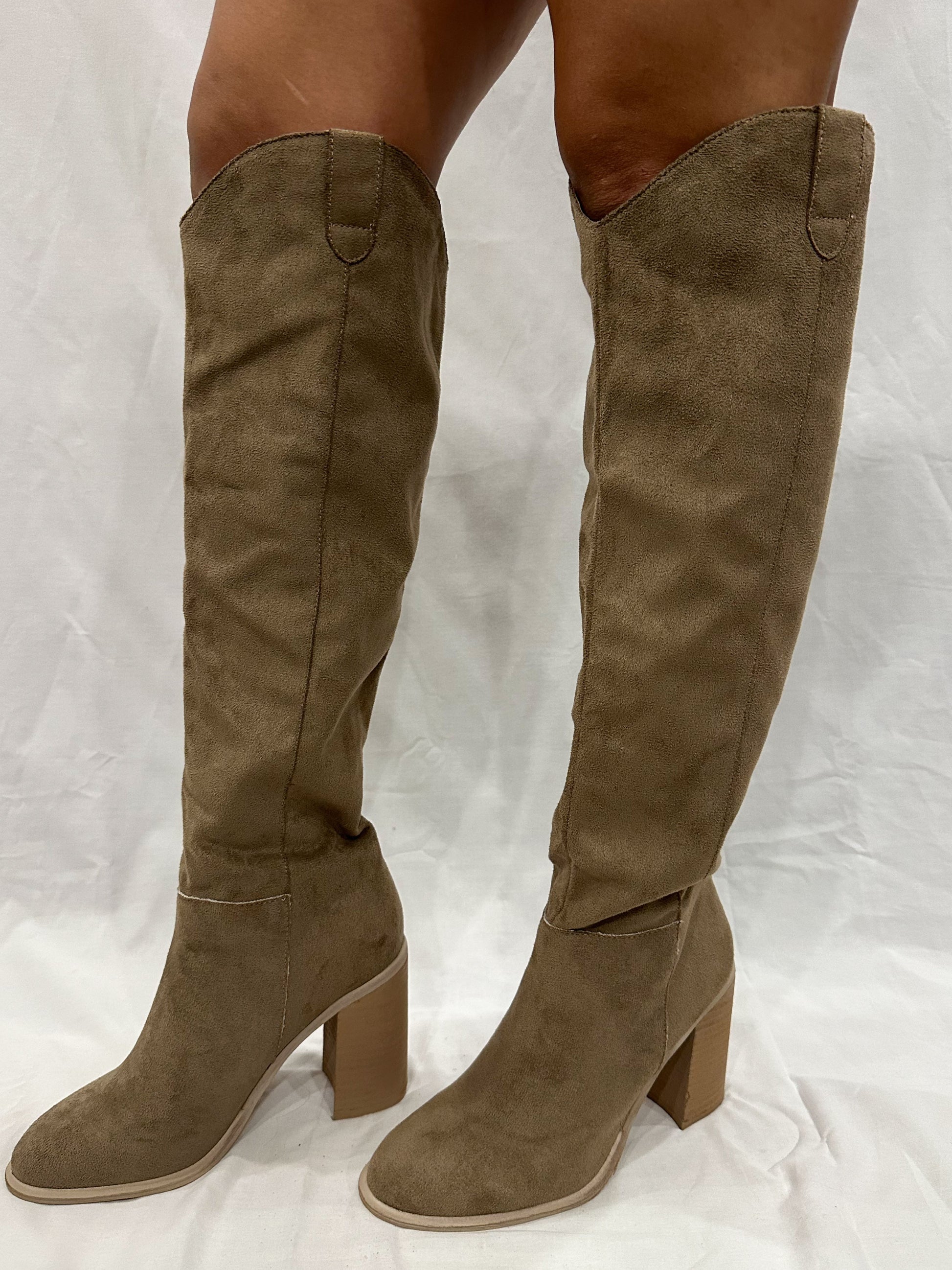 A pair of taupe grey knee-high boots with a cowgirl style, tall heel, and rounded toe.