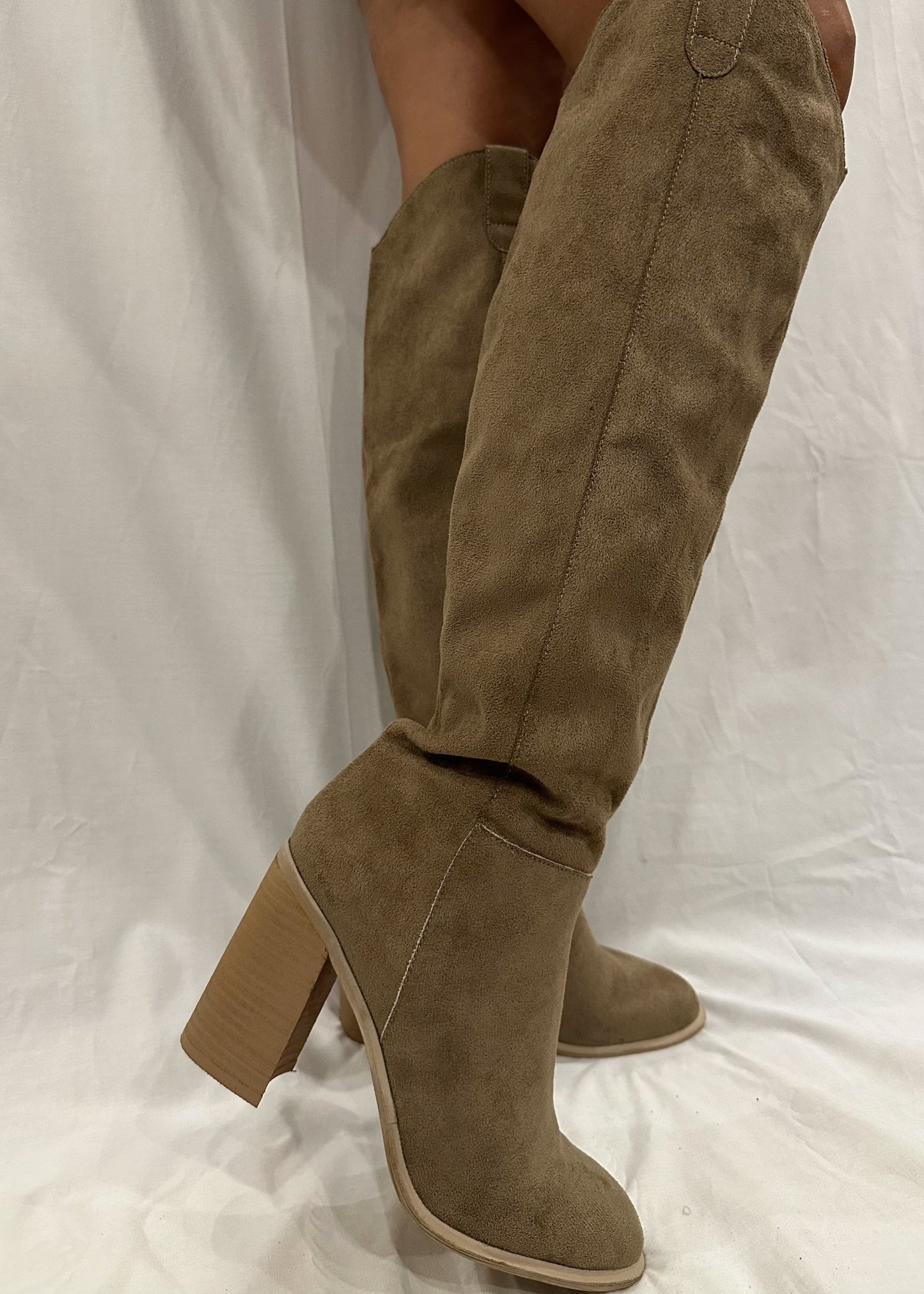 A pair of taupe grey knee-high boots with a cowgirl style, tall heel, and rounded toe.